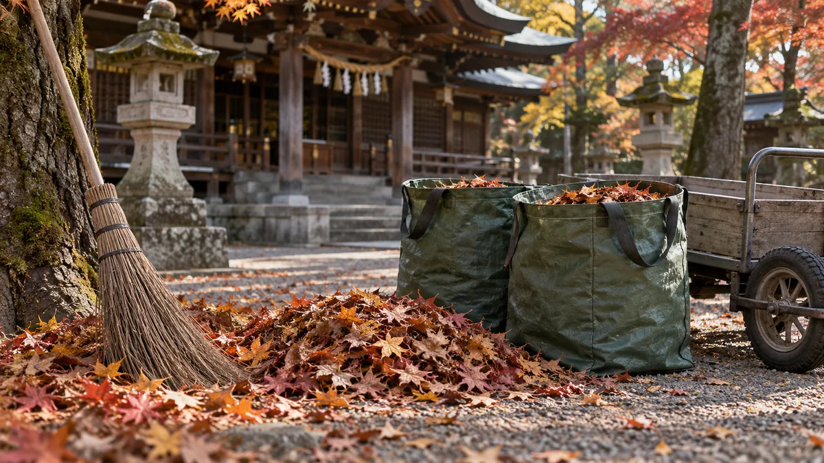 落ち葉を集めた架空の神社の境内に、ほうきと袋と台車を置いた処分準備のイメージ
