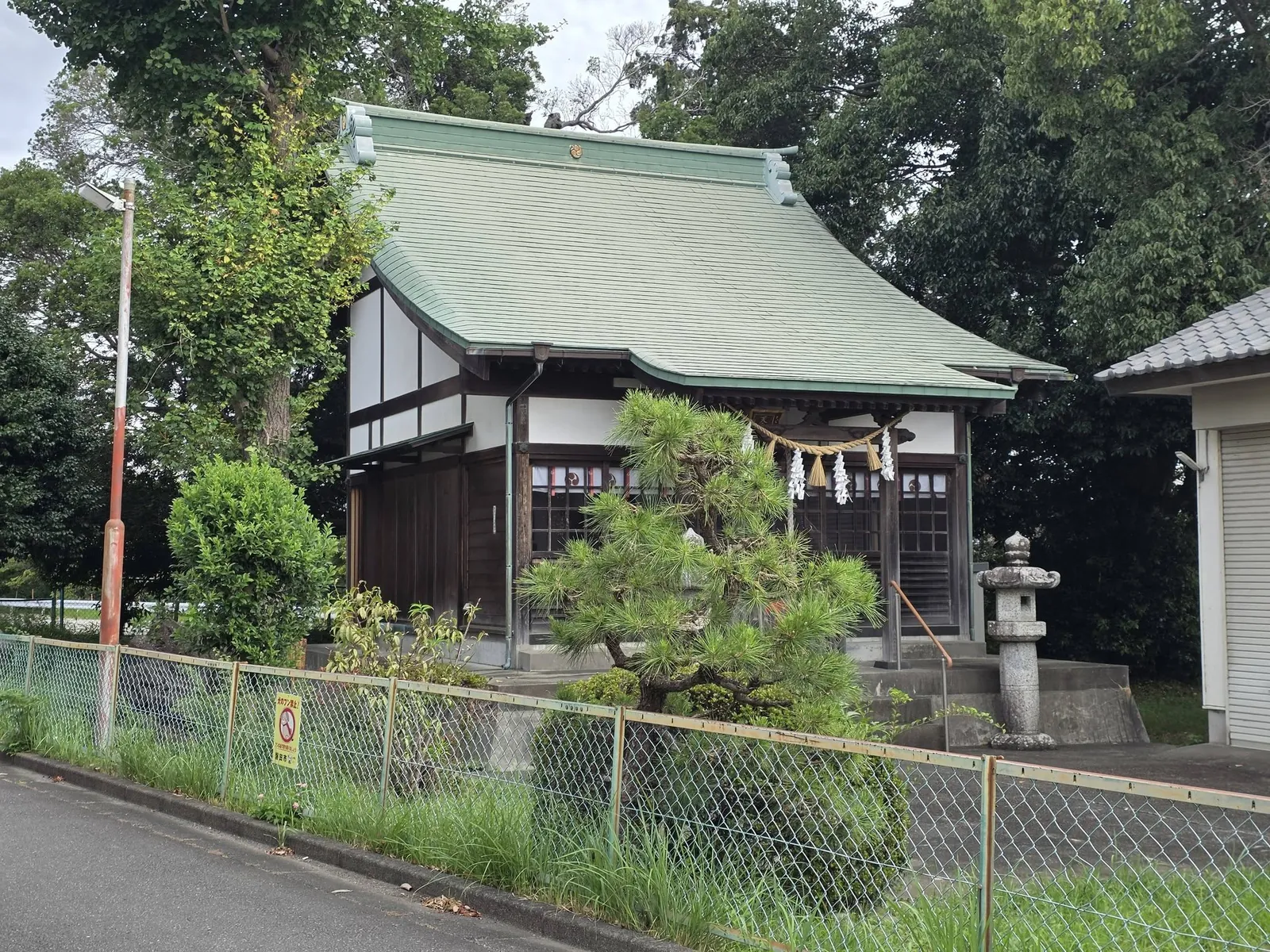 境内東側の道路から見た社殿と社叢。街なかに残る小さな鎮守の杜であることが分かる。