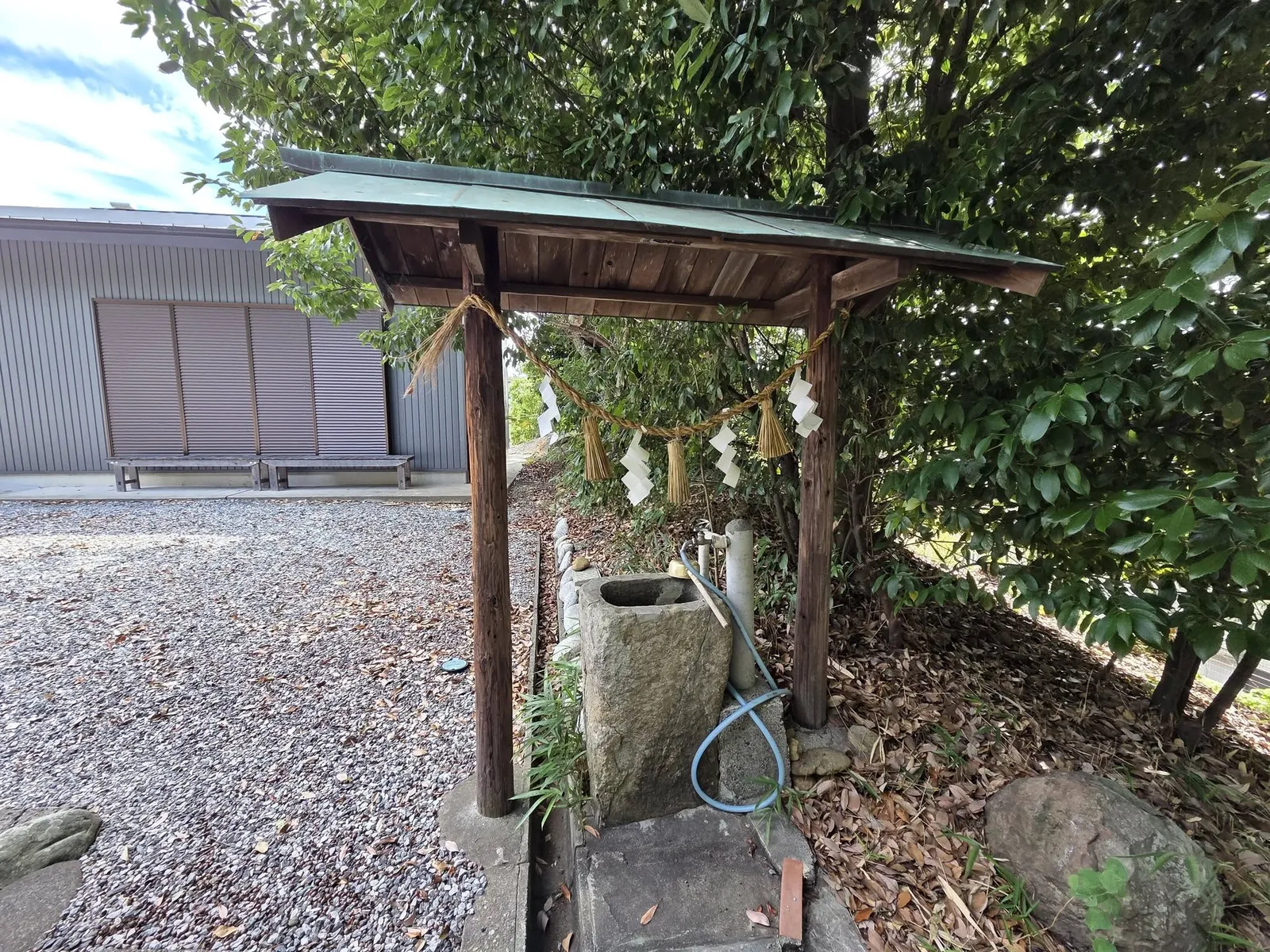 屋根付きの手水舎に置かれた石造の手水鉢。