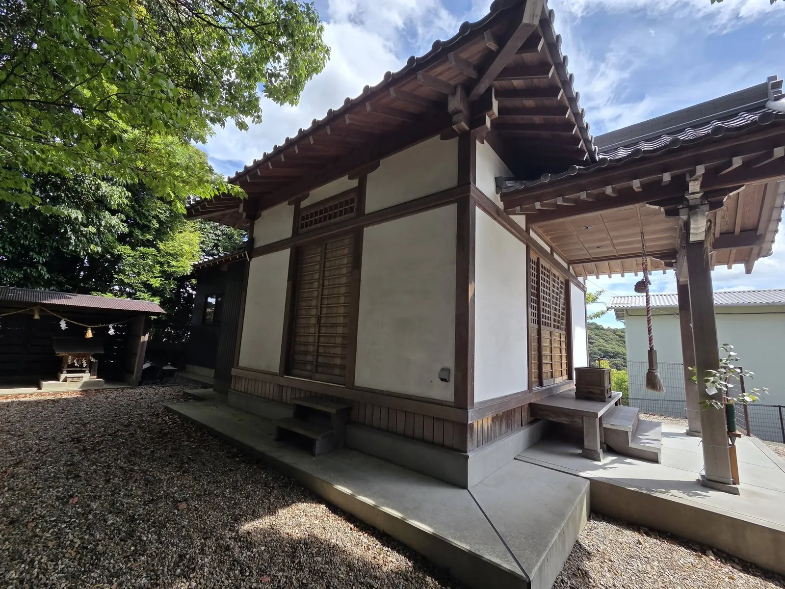 社殿の側面越しに、左手に建つ境内社の小祠を望む。