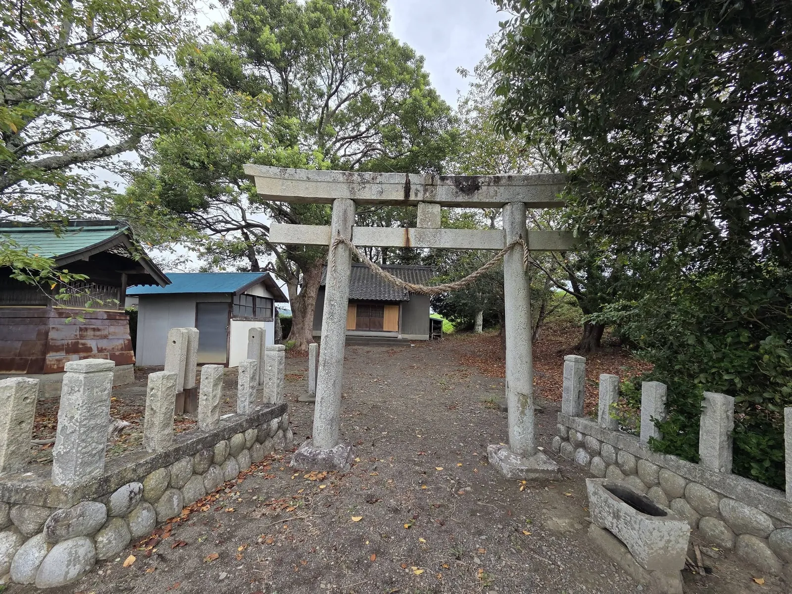 境内入口の石造鳥居。参道の先に社殿が見え、両側に石製の玉垣を巡らす。