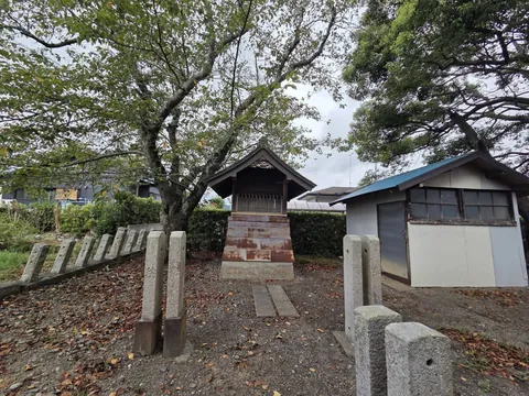 境内西側の小建物と玉垣。樹木に囲まれた境内の様子を示す。