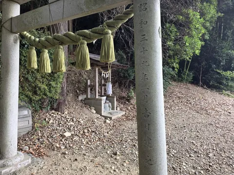 注連縄を掛けた石造鳥居と、その奥に鎮座する境内社。