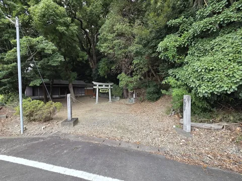 道路側から見た境内入口。社叢の奥に鳥居と社殿が見える。