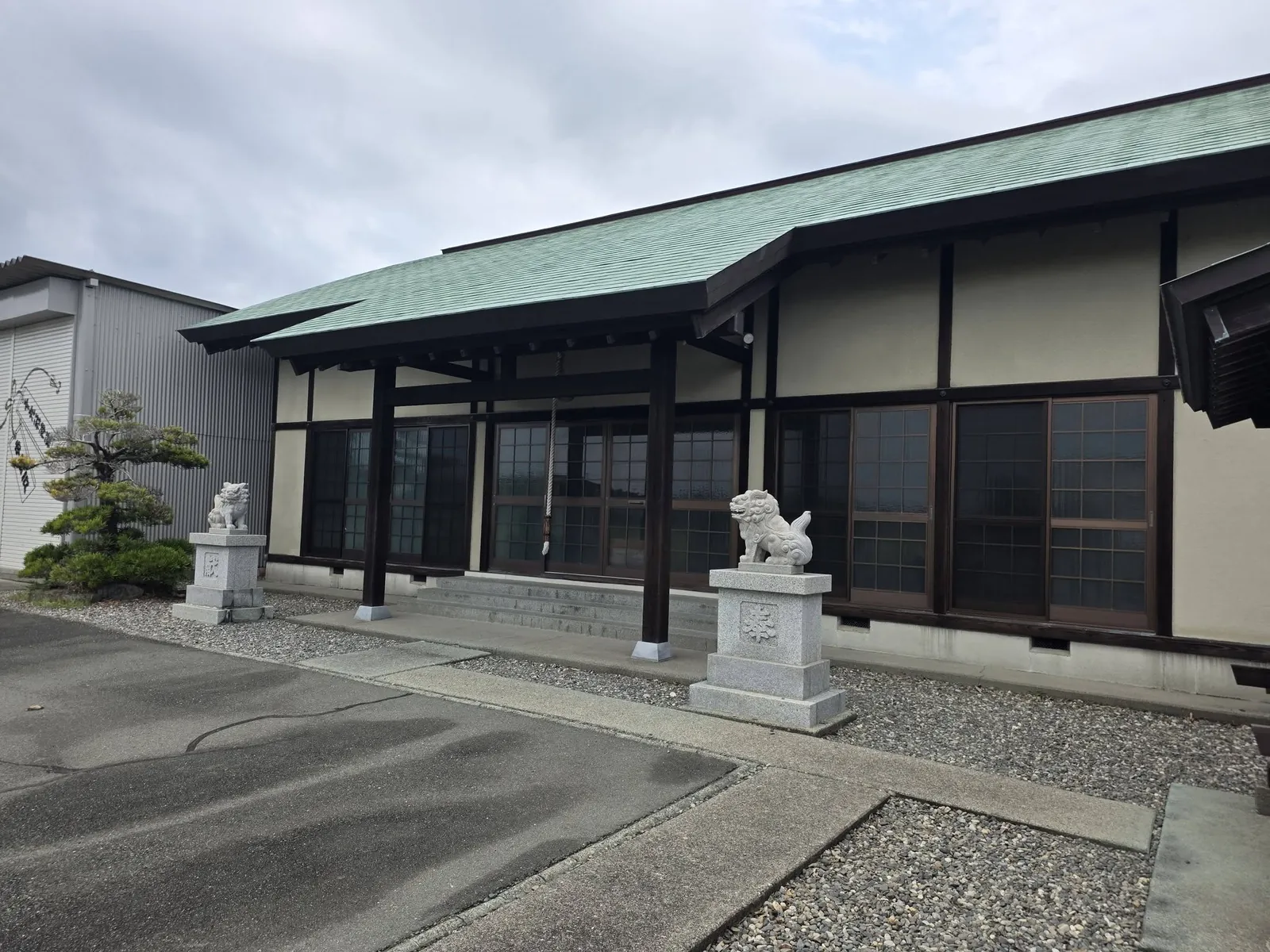 斜めから見た社殿正面。向拝前に狛犬が立つ。