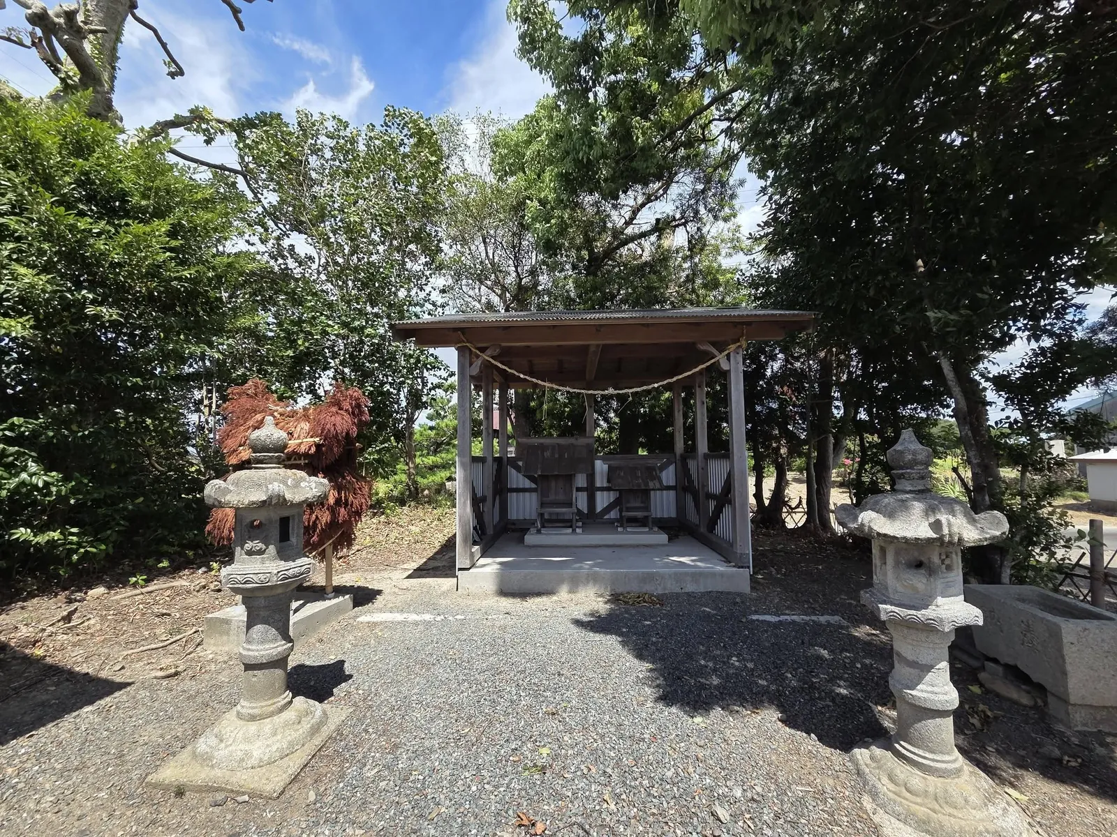 境内に建つ切妻屋根の社殿を正面やや左から見た様子。左右に石灯籠が並び、藁の飾り物が置かれている。
