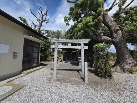 境内入口に立つ石造の鳥居を正面から見る。奥に社殿の屋根が見える。