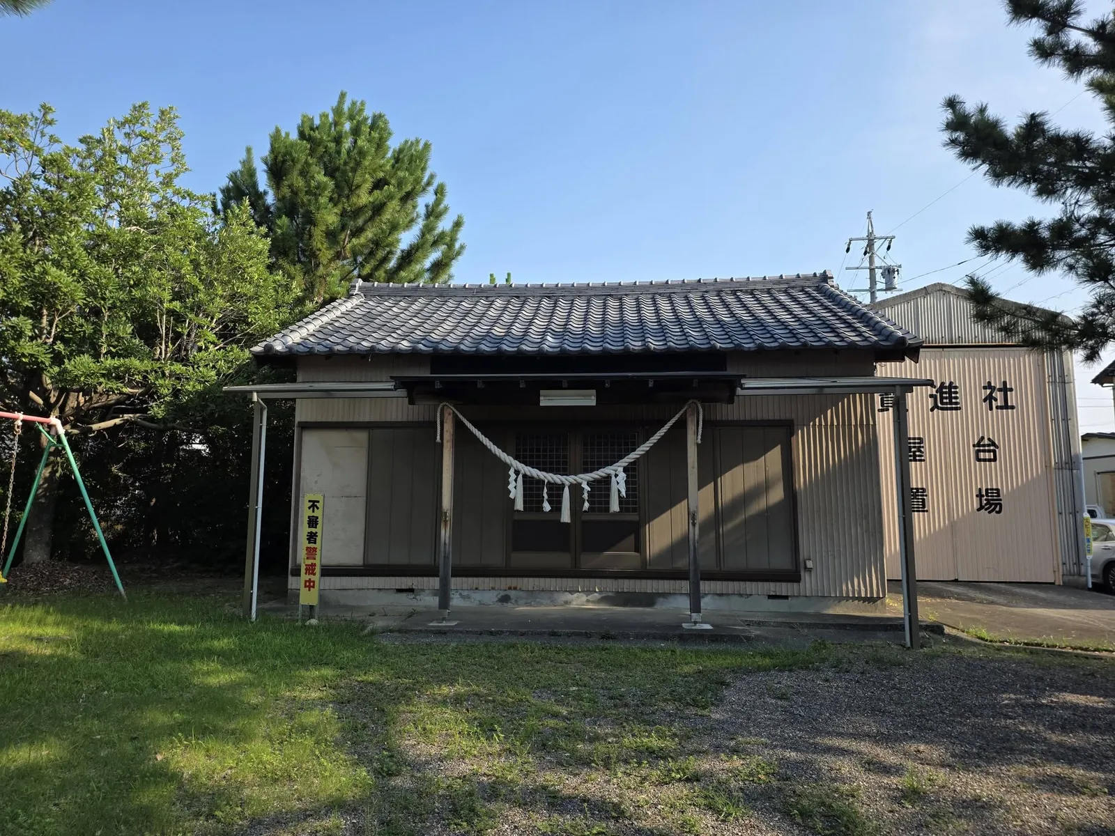 社殿正面。桟瓦葺で、前面に差し掛けの庇を設け注連縄を張る。右奥は屋台置場の建物。