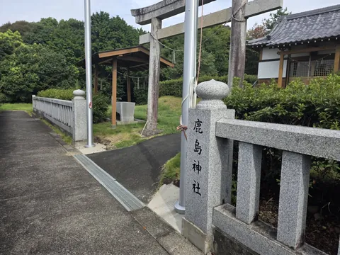 参道入口の石造鳥居と社号標。石柵の内側に社殿が見える。