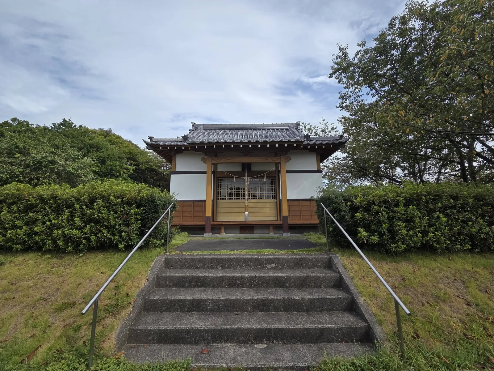 石段正面から見る社殿。瓦葺の入母屋屋根を掛ける。