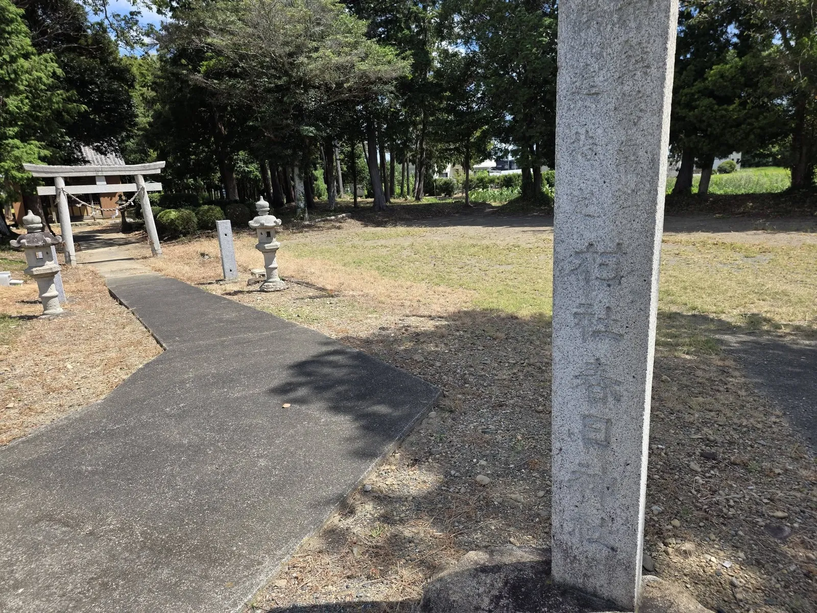 社号標の近景。奥に石灯籠と鳥居、社殿が見える境内の様子。