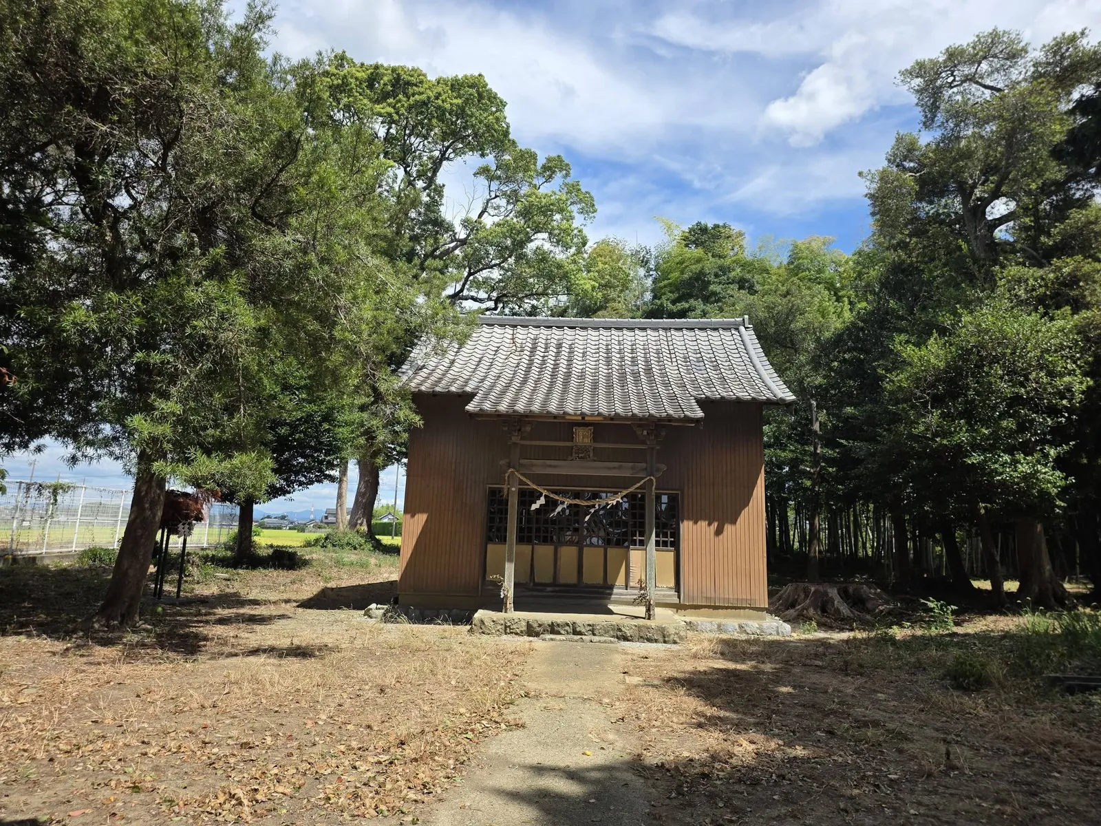 樹木に囲まれた社殿正面。屋根と扁額、注連縄が見える。