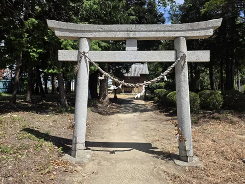 春日神社：参道正面から見た石造の鳥居。注連縄の奥に社殿が見える。