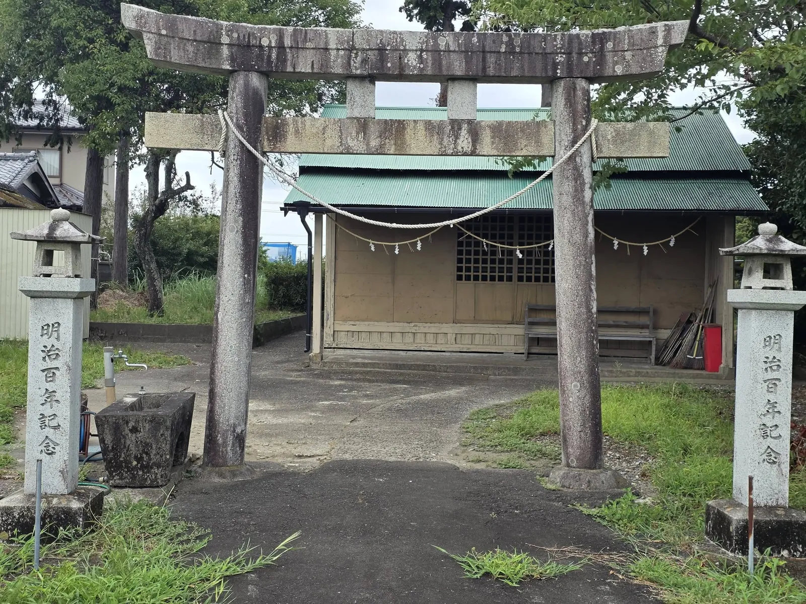 石造鳥居の正面から社殿を望む。鳥居脇に石灯籠が立つ。