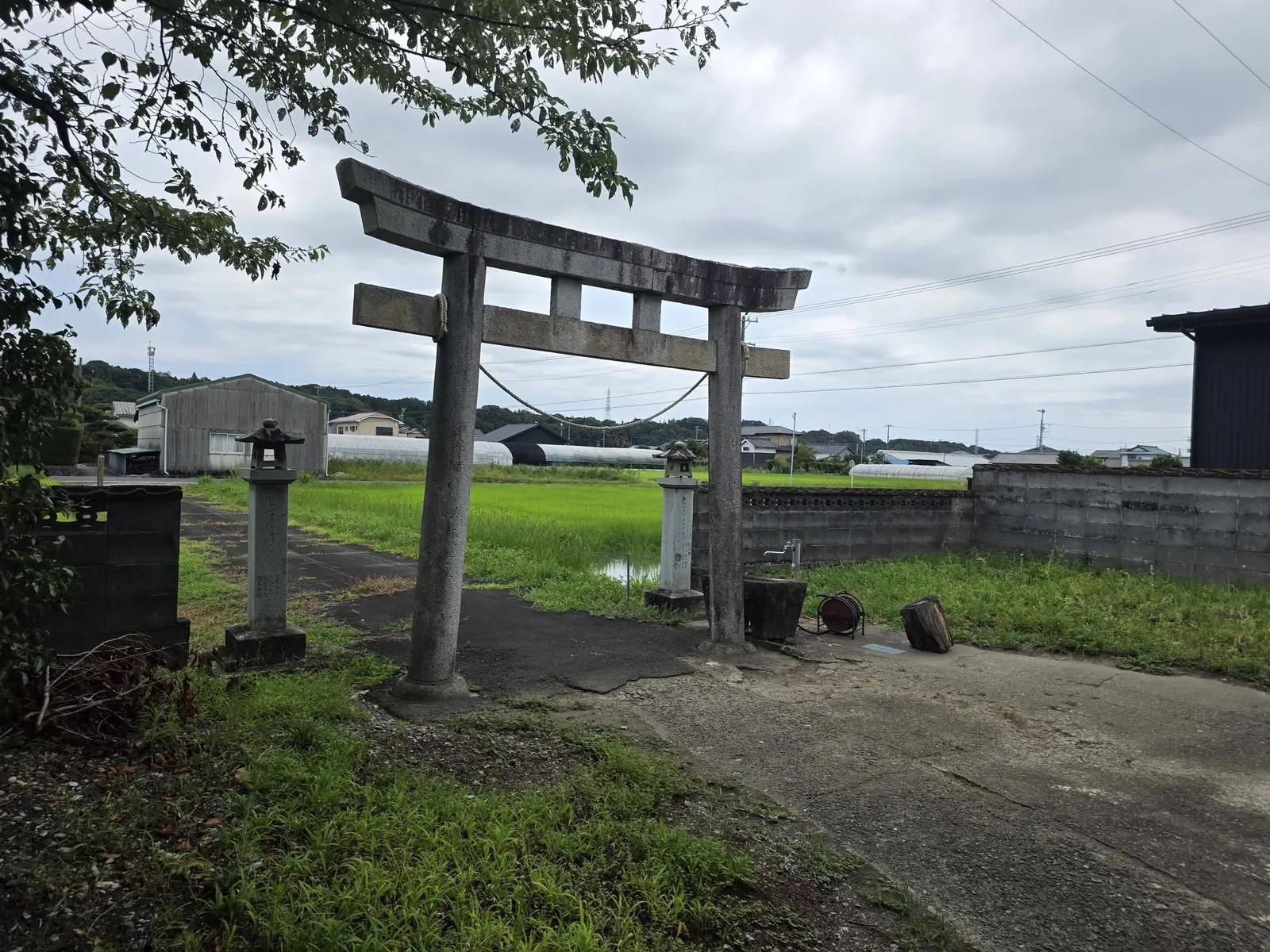 境内側から見た石造鳥居と周囲の田園景観。