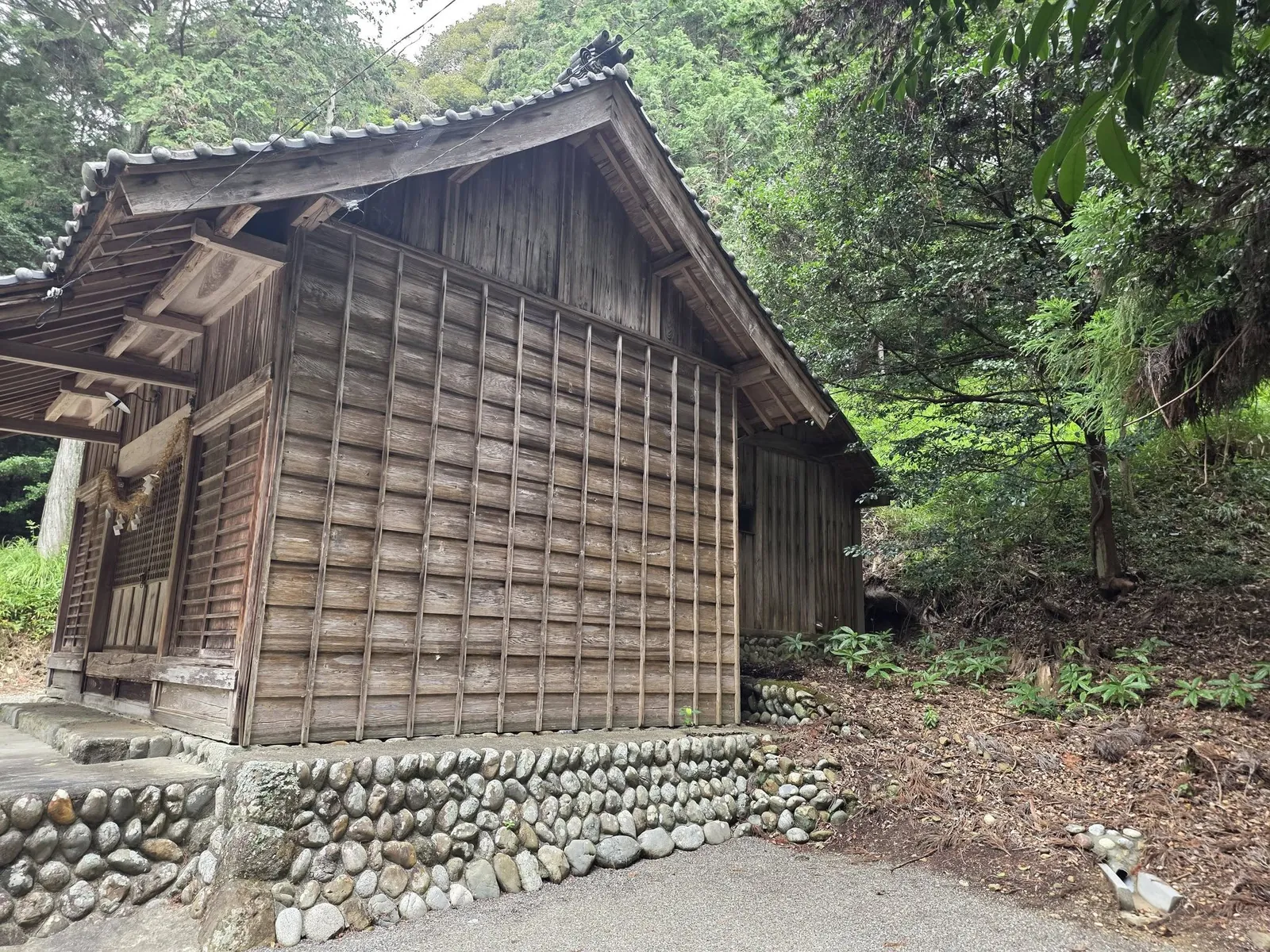 社殿側面。板張りの外壁と玉石積みの基壇を記録する。