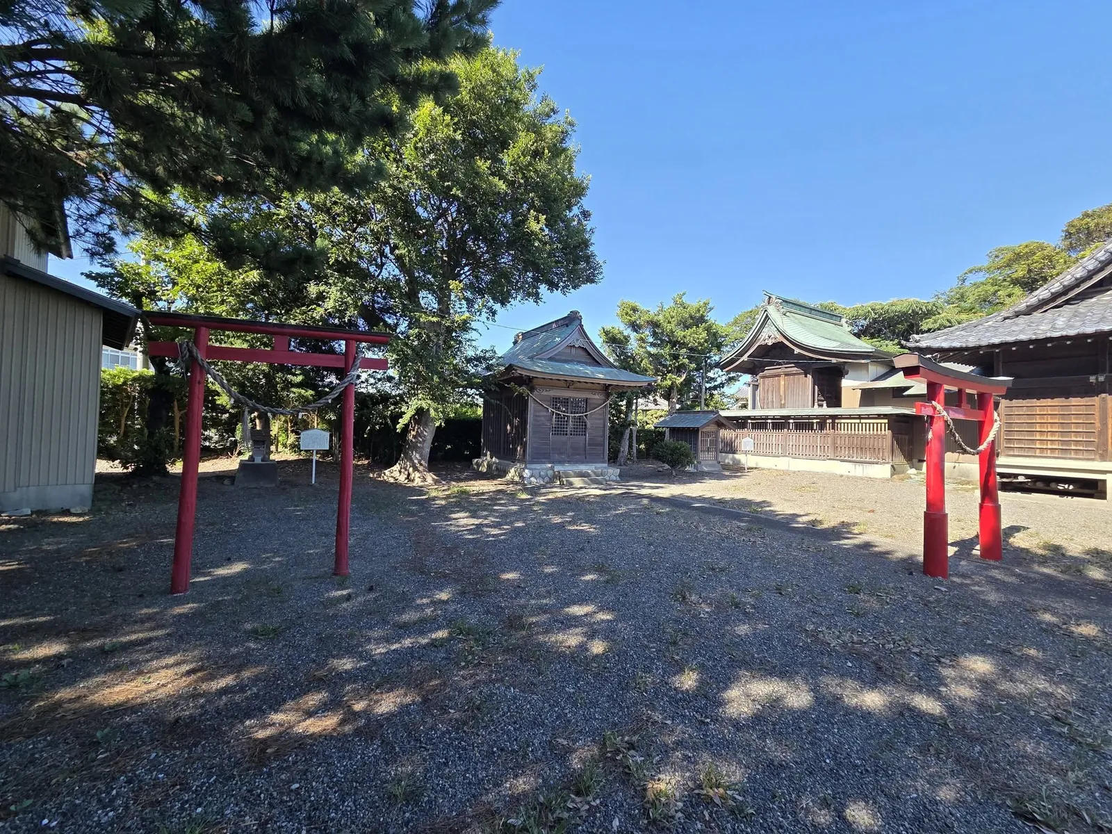 朱塗りの鳥居と境内社、社殿が並ぶ境内。