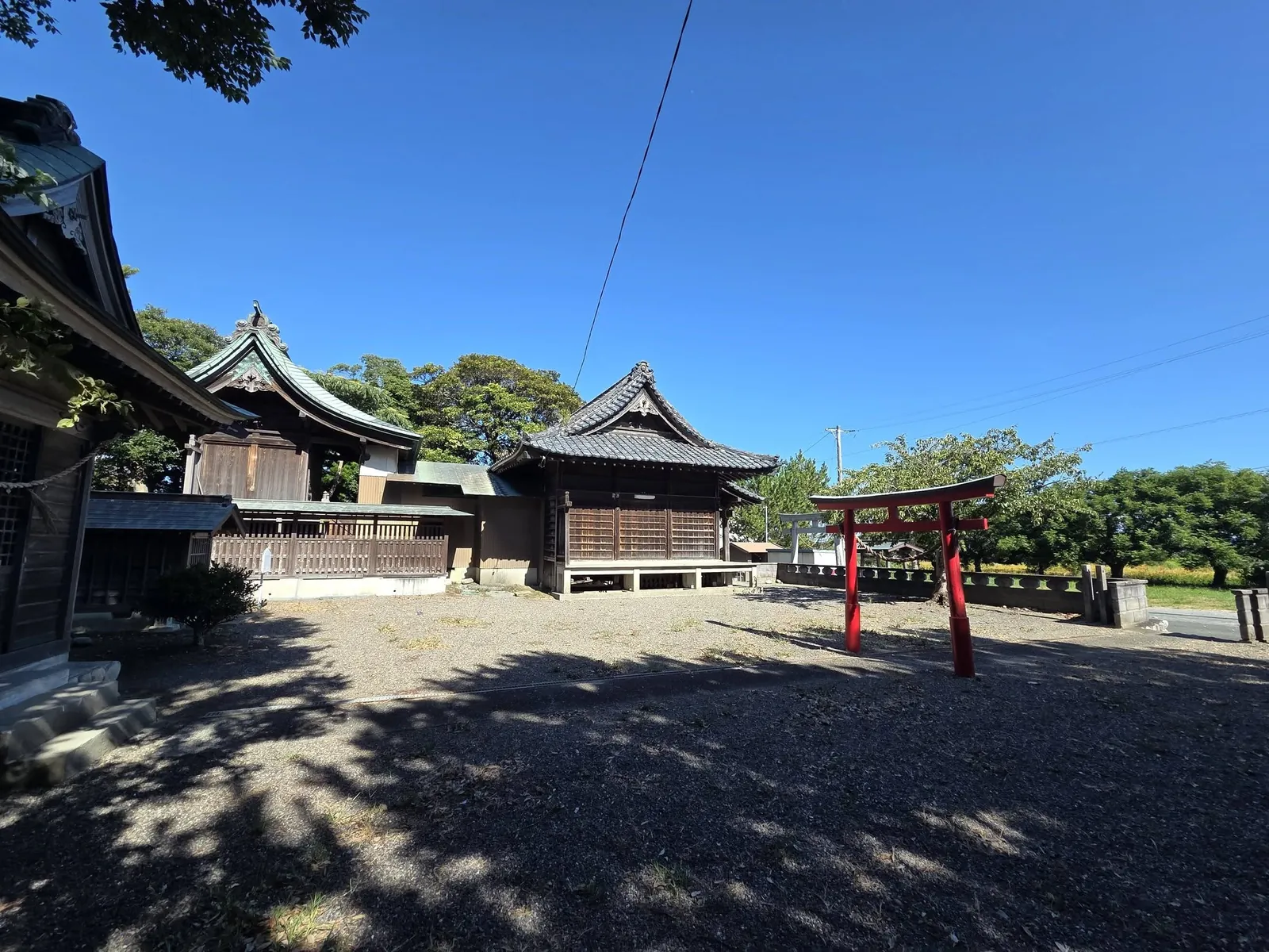 側方から見た駒場神社の社殿と朱塗りの鳥居。