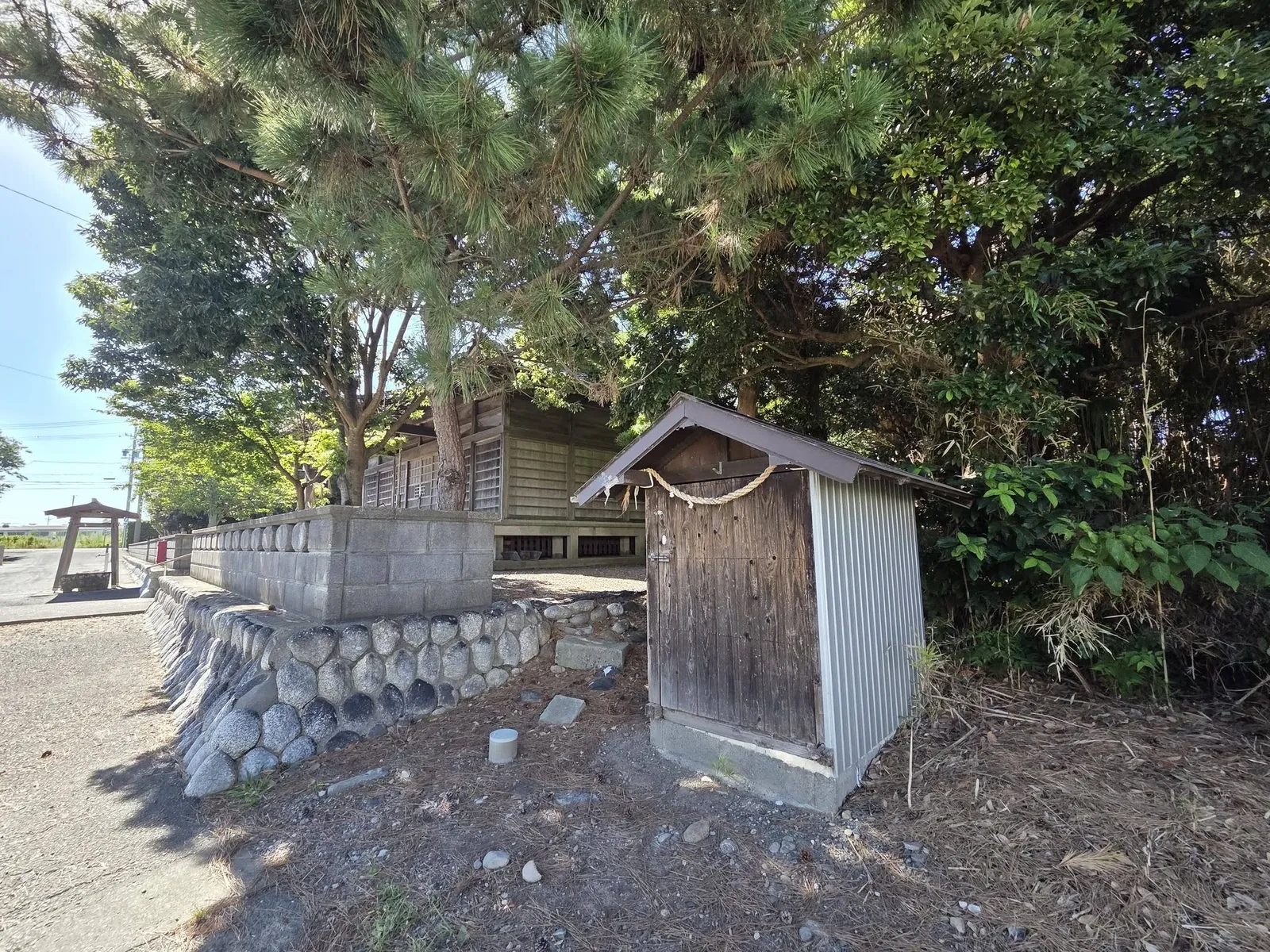 社叢の縁に建つ注連縄を掛けた小祠。