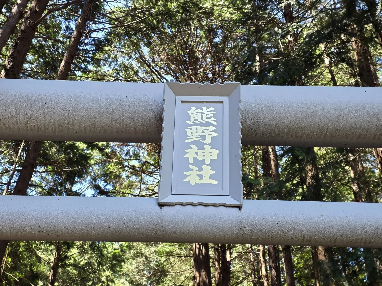 白い鳥居に掲げられた「熊野神社」の神額。