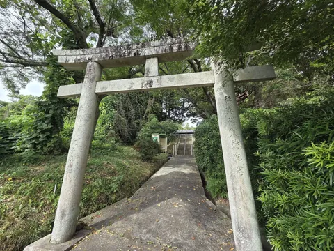 石造鳥居の近景。柱の脇に「熊野神社」と刻む社号標が立つ。
