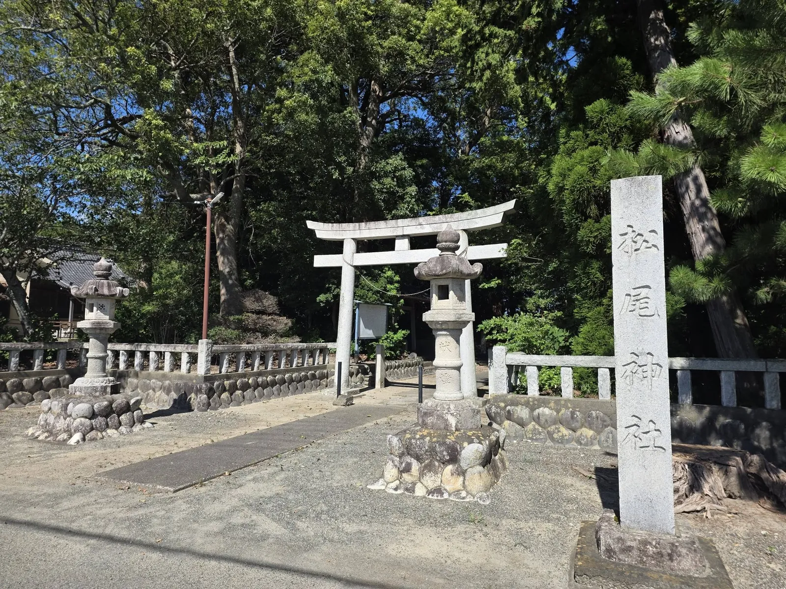 社号標・石灯籠・石造鳥居が並ぶ松尾神社の境内入口。