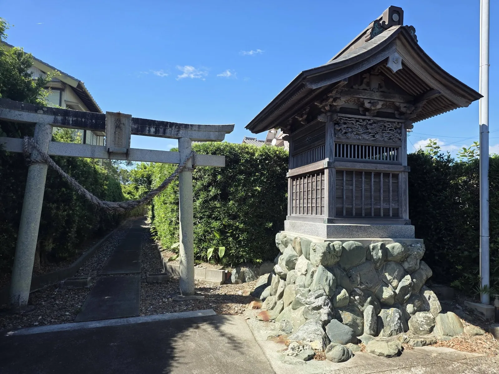 石造鳥居と参道入口。右手に木造の建物が立つ。