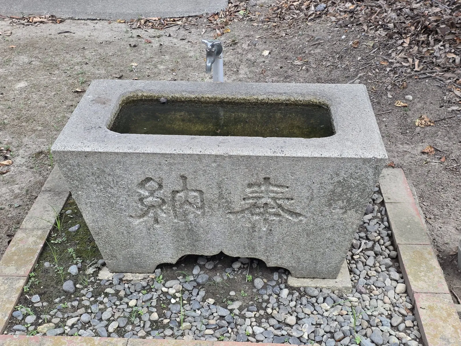 「奉納」と刻まれた石造の手水鉢。