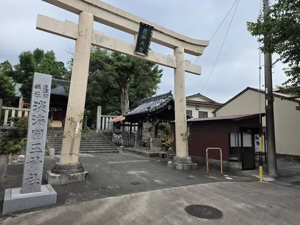 社号標と石造鳥居を正面から見る。鳥居の奥に参道と神門が続く。