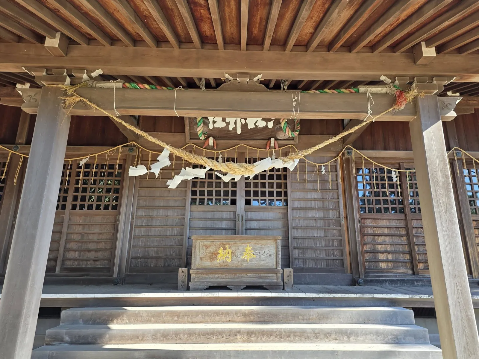 向拝の下から見た拝殿正面。注連縄と扁額を掲げる。