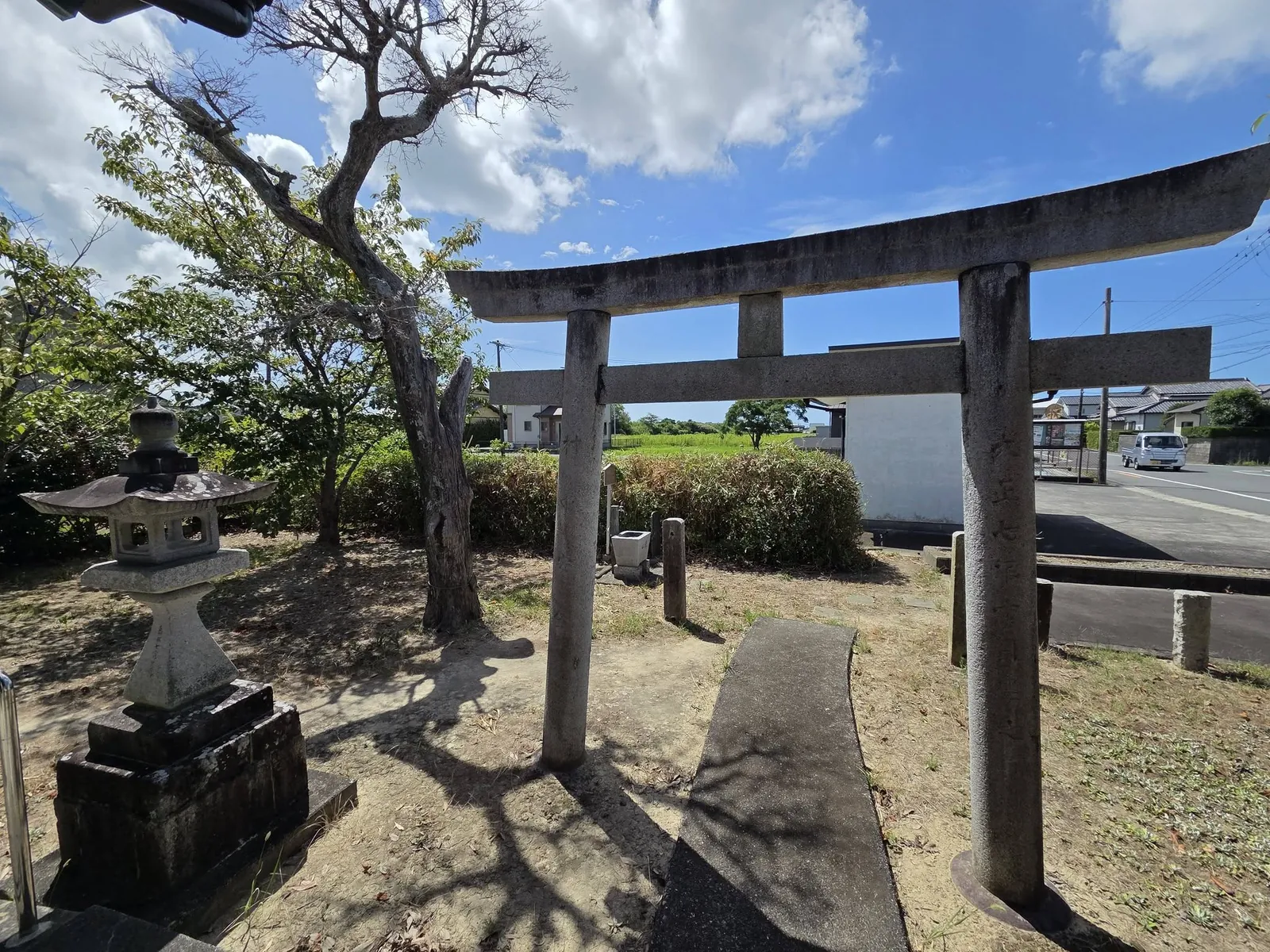 境内側から石造鳥居と道路沿いの田園を望む。