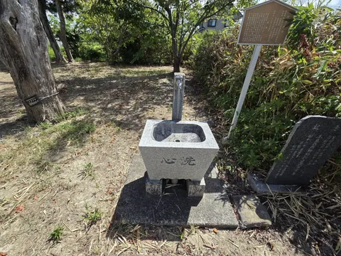 由緒掲示のそばに置かれた手水鉢。正面に「洗心」と刻む。