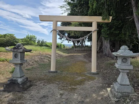 六所神社：参道入口に立つ鳥居。柱の間にしめ縄と紙垂が渡され、両脇に一対の石灯籠が置かれている。