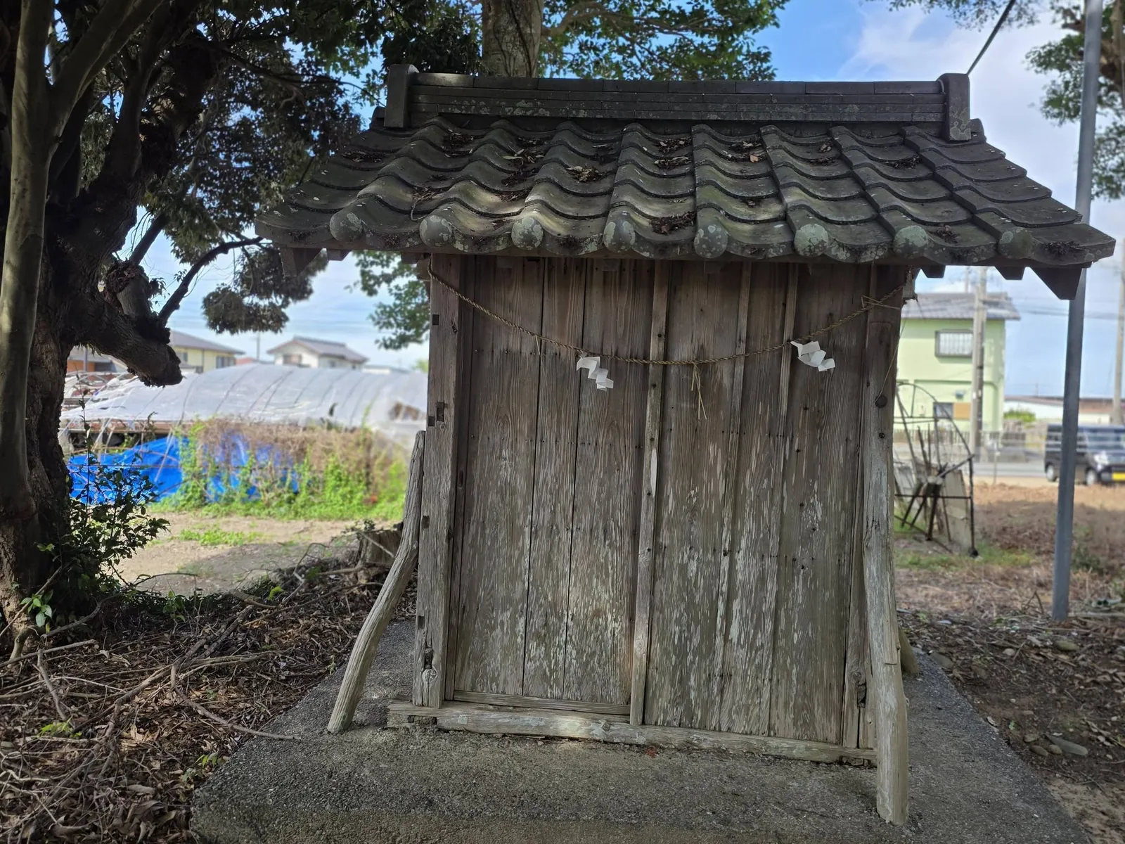境内社(祠)の正面。瓦葺きの屋根と木製の扉、しめ縄と紙垂が見える。
