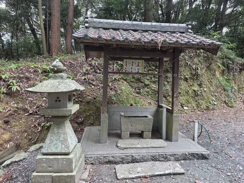 境内の手水舎と石灯籠。木造屋根の下に石造手水鉢を据える。
