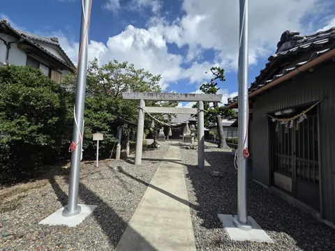 境内入口の幟竿の間から、石造鳥居と社殿を望む。