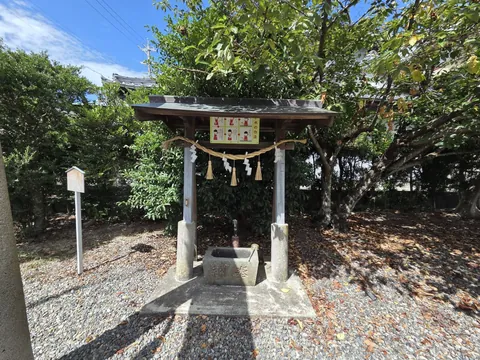 木立のそばに建つ手水舎と手水鉢。