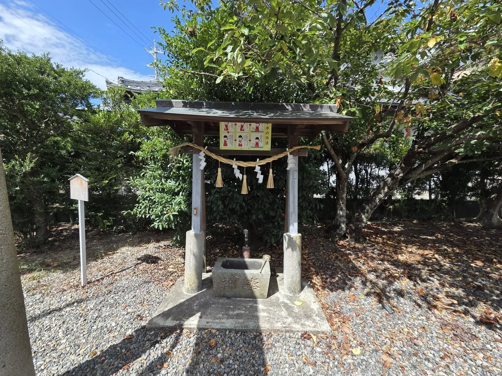 木立のそばに建つ手水舎と手水鉢。