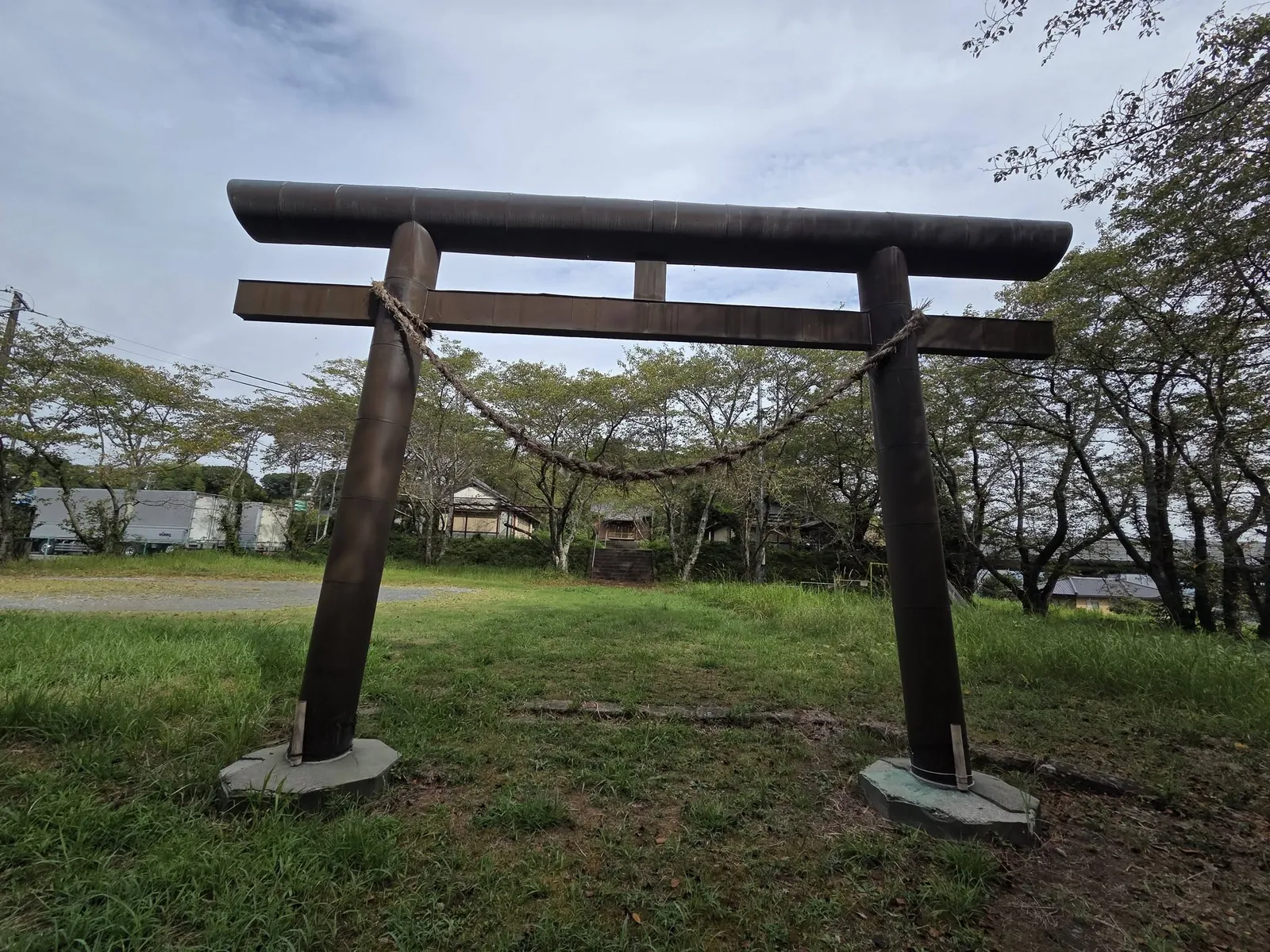境内入口の木造鳥居。草地の参道の先に社殿が見える。