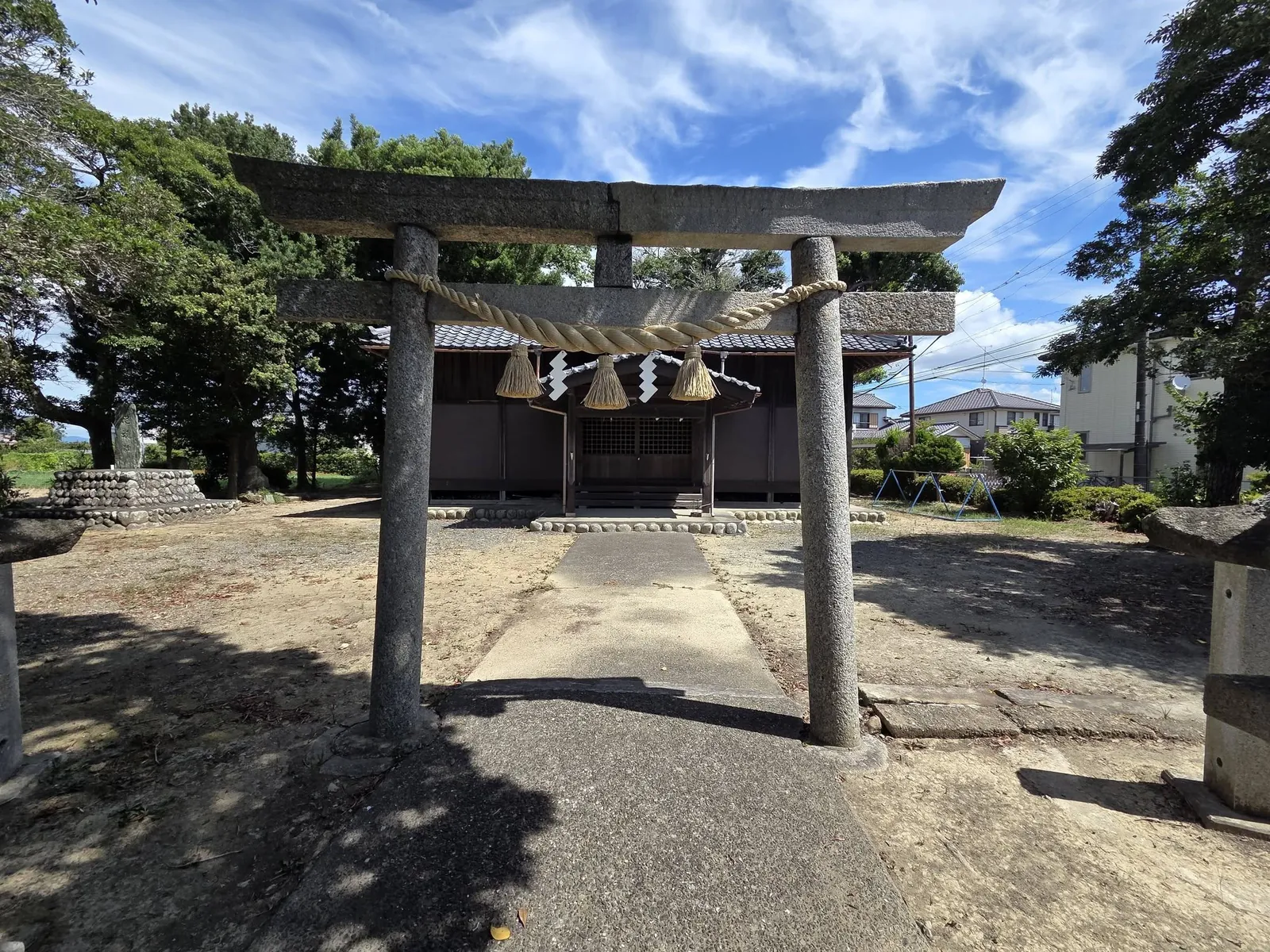 参道正面から見た石造鳥居。しめ縄と紙垂の奥に社殿が見える。