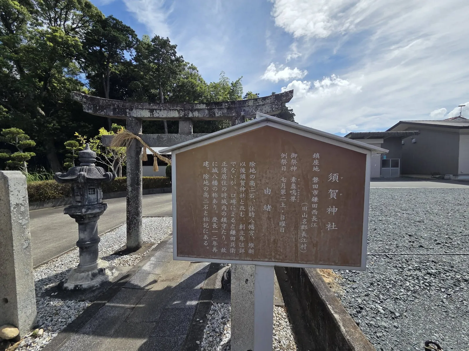 参道入口に立つ「須賀神社」の由緒板。祭神・例祭日・由緒を記す。奥に鳥居と灯籠が見える。