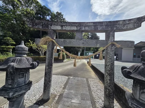 参道正面から見た石造鳥居。注連縄を張り、両脇に灯籠を配する。
