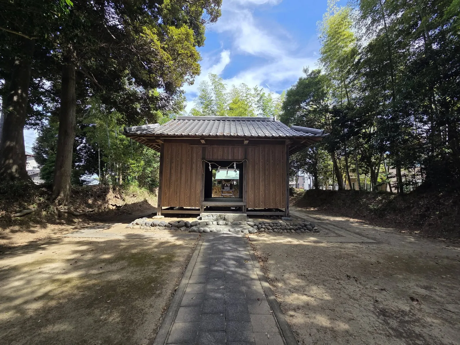参道正面から見た須賀神社の社殿。瓦葺きの入母屋屋根で、石積みの基壇に建つ。