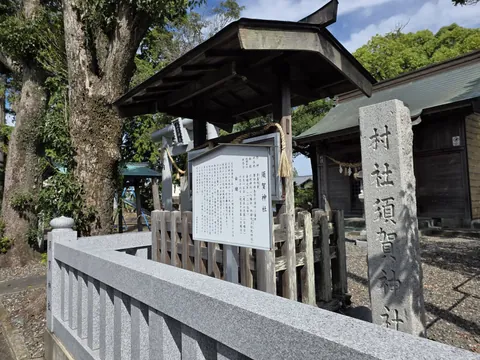 「須賀神社」の由緒板と「村社須賀神社」の社号標。奥に鳥居と社殿を望む。