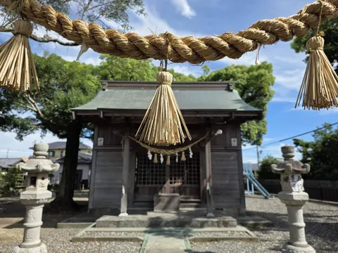 一対の石灯籠越しに見た社殿正面。注連縄と紙垂が渡され、奥に格子戸が見える。