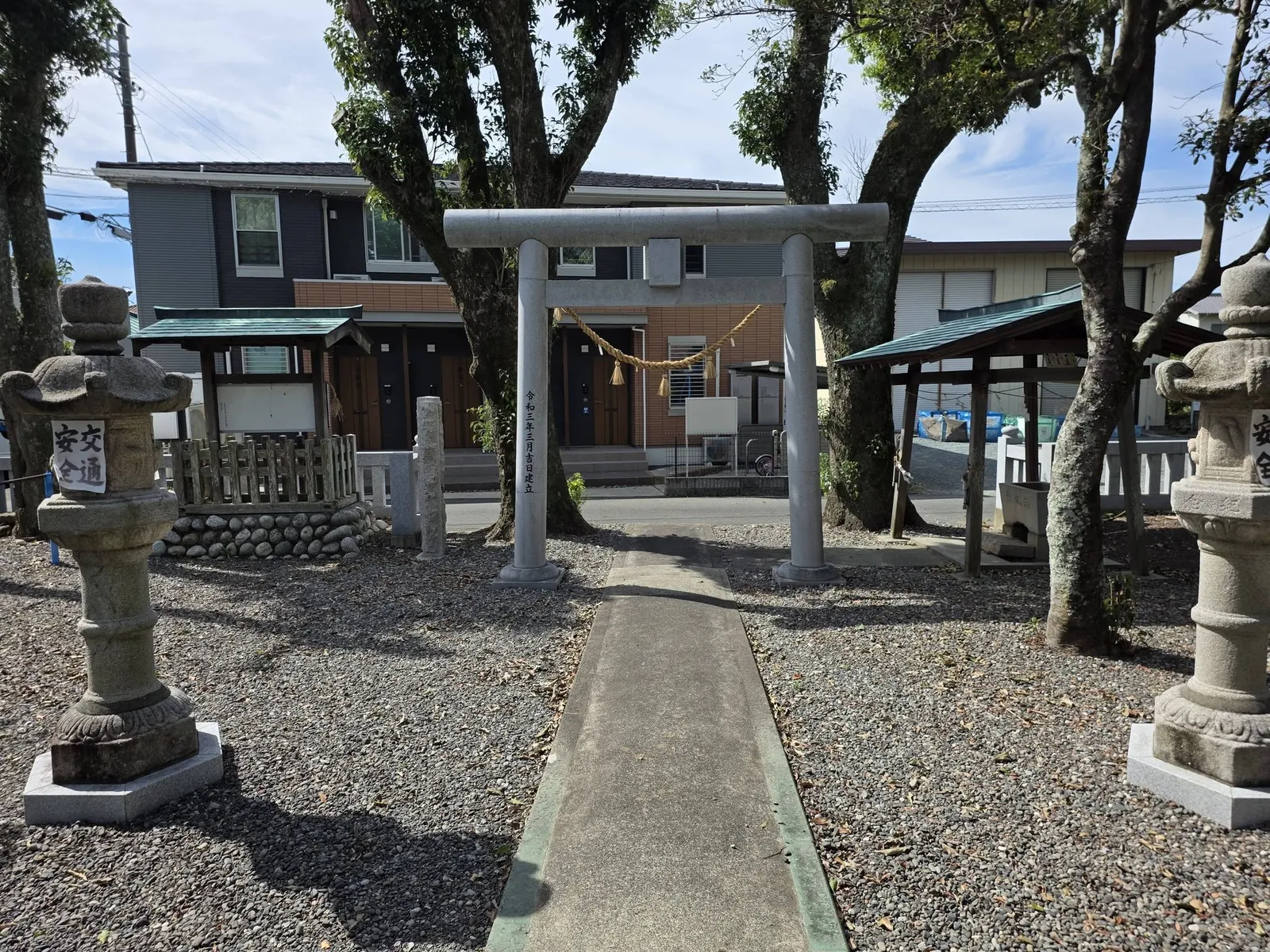 境内から鳥居越しに見た道路と住宅街。社叢と集落の近さが分かる。