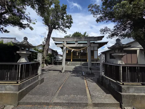 一対の石灯籠に挟まれた石造鳥居を参道正面から見る。注連縄の奥に社殿が見える。