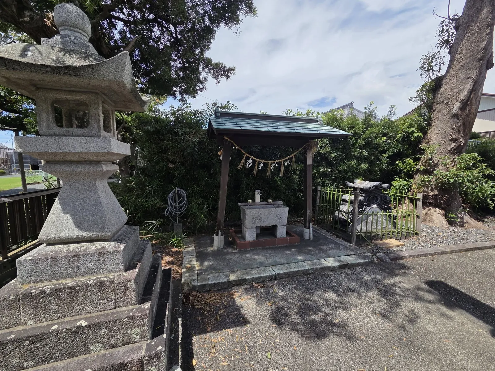 屋根付きの手水舎と石灯籠。手水鉢には「奉納」の文字が刻まれている。