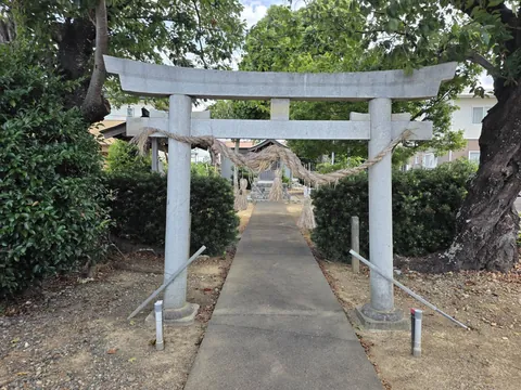 水神社：参道入口の石造鳥居。注連縄を張り、正面奥に社殿が見える。