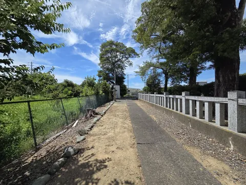 石造玉垣沿いに続く参道。左手に水田、奥に社殿へ続く道が見える。